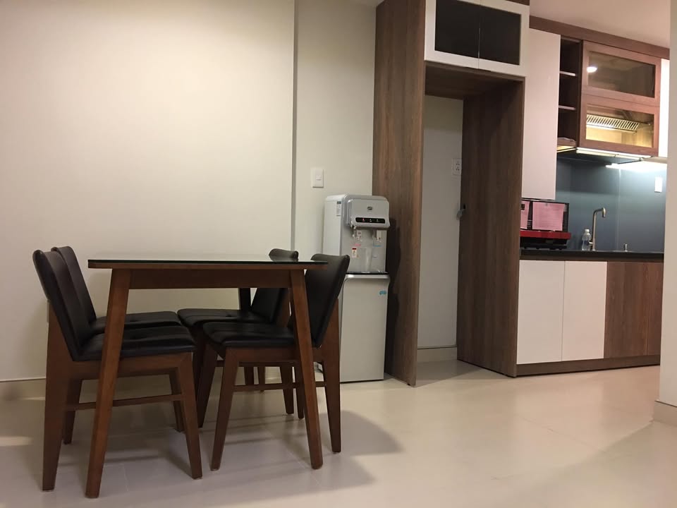 Bàn ăn mặt kính bốn ghế gỗ đặt cạnh khu bếp