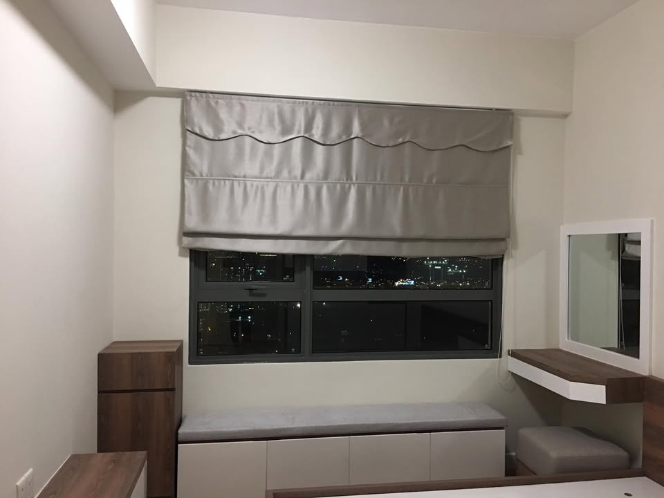 Phòng ngủ có rèm Roman xám và ghế nệm bệ cửa sổ kèm hộc kéo